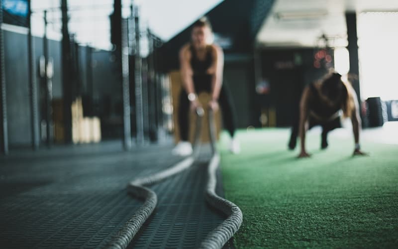 Athletin trainiert mit Battle Ropes im Gym – Konsequenz und Dranbleiben im Fitness-Coaching